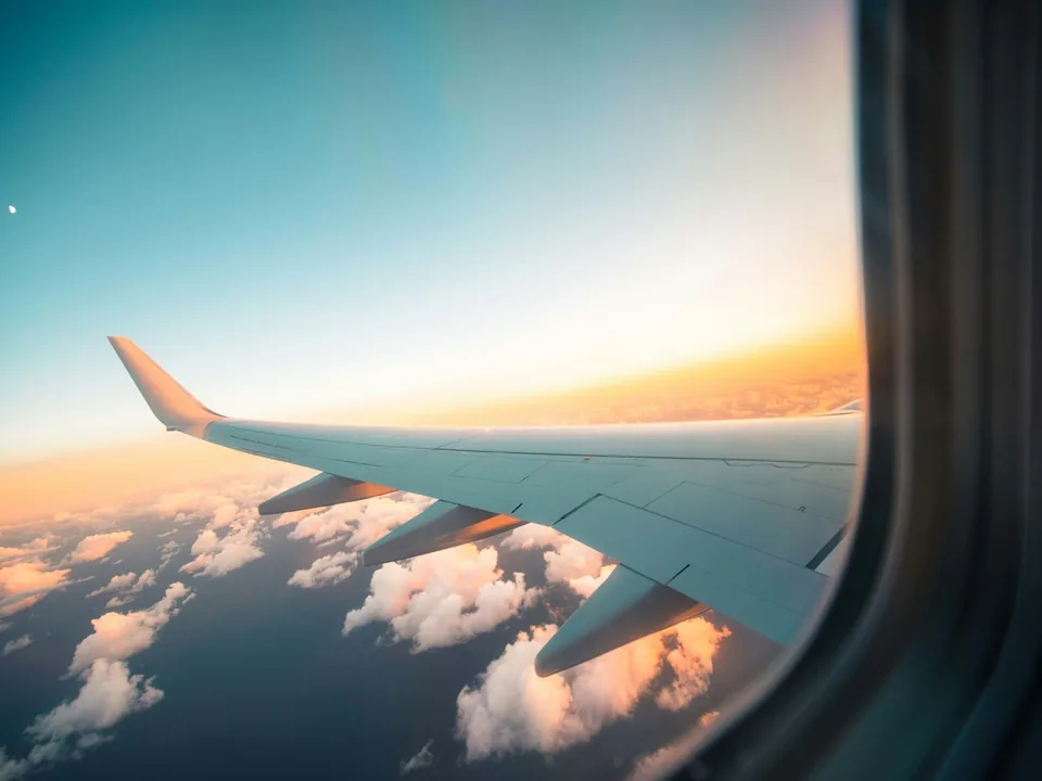 A plane wing above the clouds at sunset